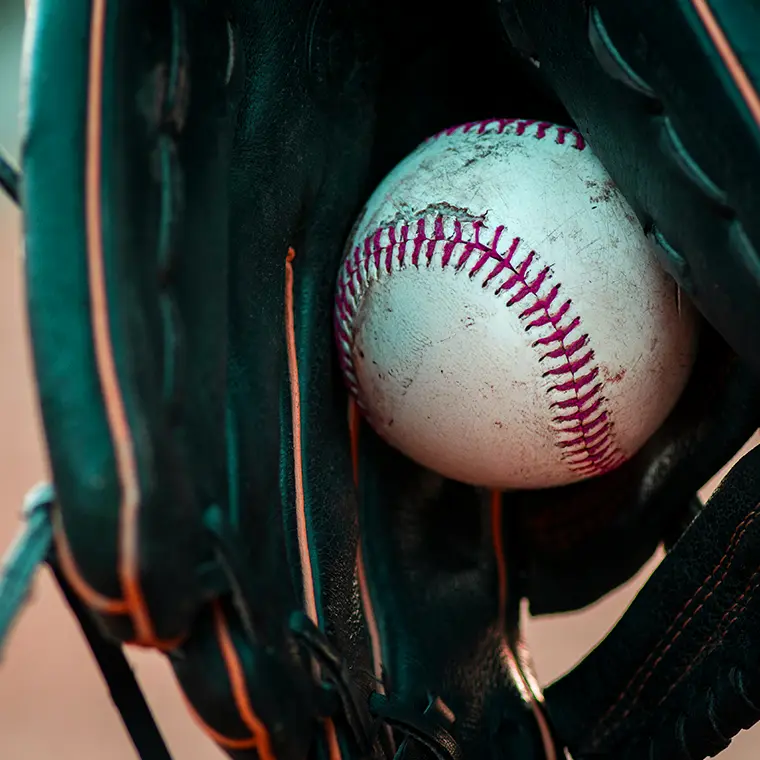 Close-up of a worn baseball resting in a leather glove