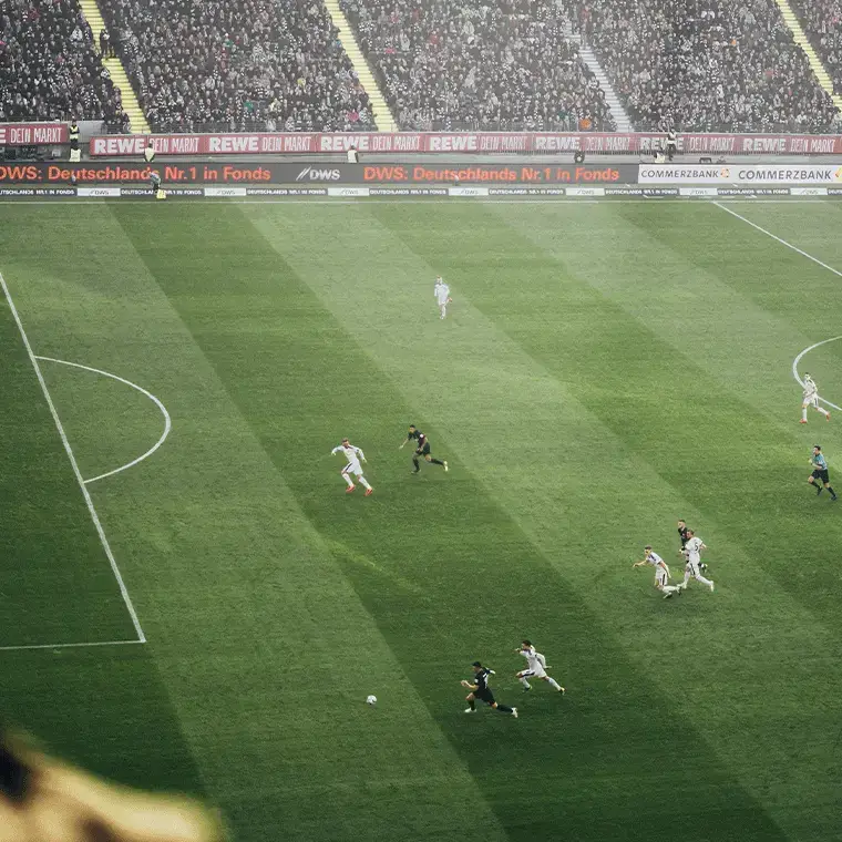 Soccer match in progress with players sprinting toward the ball as a packed stadium looks on