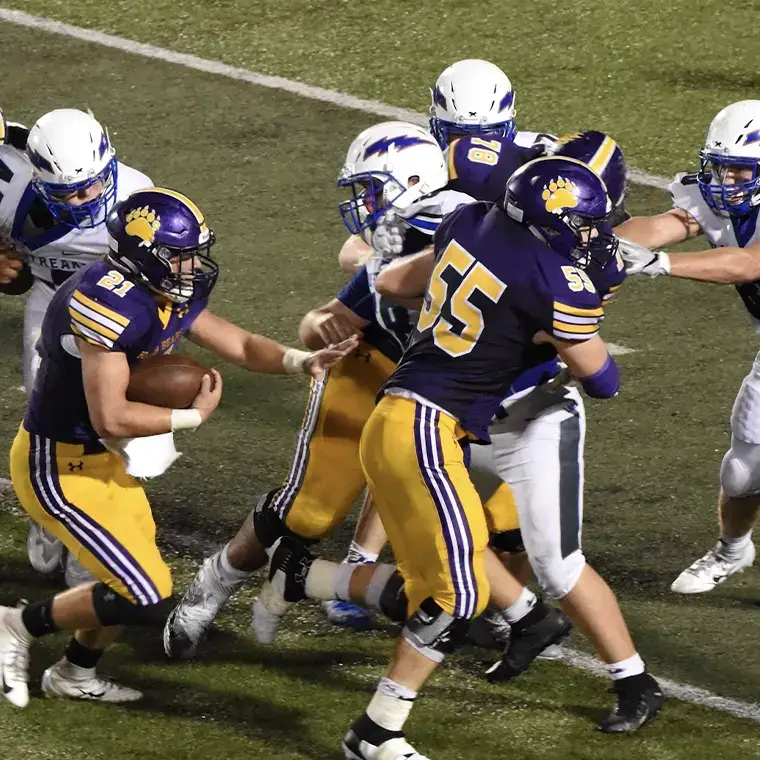 High school American football game showing players in action during a running play